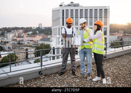 Team, das sich ein kleines Modell eines Wohngebäudes im Freien ansieht Stockfoto