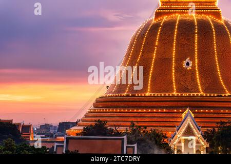 Fromme buddhisten klettern auf die goldene Pagode Phra Pathom Chedi, die jedes Jahr auf dem Nakhon Path gefeiert wird, um die Lichterdekoration am farbenfrohen Sonnenuntergangshimmel zu bewundern Stockfoto