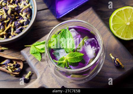 Erfrischendes Sommergetränk, geeister Bio-Blaue und violette Schmetterlingserbsenblüten-Tee mit Minze und Limette. Niedriger Flachfokus Stockfoto