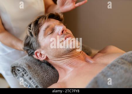 Entspannter Mann, der eine Nackenmassage von einem Therapeuten mit verschwommenen Händen erhält Stockfoto