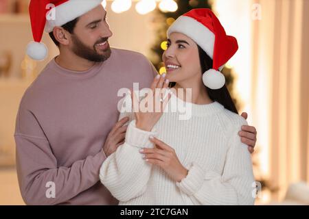 Vorschläge machen. Glückliche Frau mit Verlobungsring und ihr Verlobter zu Hause zu Weihnachten Stockfoto