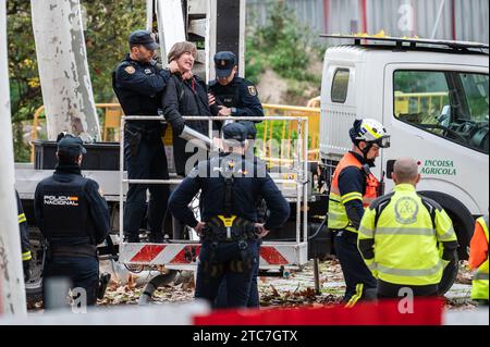 Ein Klimaaktivist, der mit Metallrohren an einen Kran gekettet ist, wird von der Nationalpolizei während eines Protestes gegen das Fällen von Bäumen entfernt. Nachbarn und die Umweltorganisation Extinction Rebellion protestierten, nachdem heute im Arganzuela Park in Madrid Rio der Holzschlag begonnen wurde, aufgrund der Erweiterungsarbeiten an der U-Bahn-Linie 11. Der Protest fällt mit der Feier des Klimagipfels COP28 zusammen, der bis zum 12. Dezember in Dubai stattfindet. Aktivisten haben auch die Untätigkeit der Regierungen angeprangert, Maßnahmen gegen den Klimawandel zu ergreifen, und sehen das Verschwinden von Bäumen im urbanen Kontext als einen Fut Stockfoto