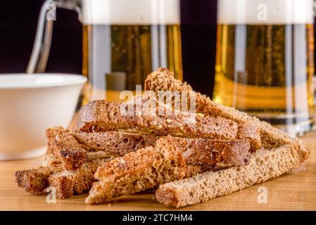 Nahaufnahme knuspriger Knoblauchcroutons vor dem Hintergrund von Glasbecher Bier. Leckerer Snack für Bier. Stockfoto