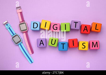 Phrase Digital Autismus aus bunten Würfeln und Smartwatches auf violettem Hintergrund, flache Lay. Suchtverhalten Stockfoto