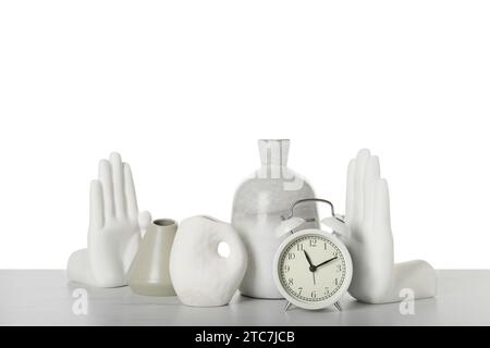 Verschiedene stilvolle Vasen, Wecker und andere Dekoelemente auf dem Tisch vor weißem Hintergrund Stockfoto