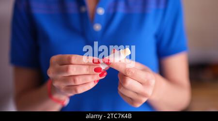 Frau mit roter Maniküre hält hygienischen Lippenstift in den Händen Nahaufnahme Stockfoto