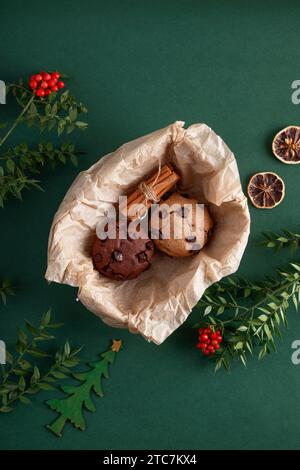 Weihnachtsblumen und Kekse im Korb auf isoliertem grünen Hintergrund Stockfoto
