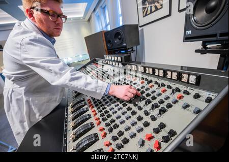 London, Großbritannien. Dezember 2023. Die EMI TG12345 Mk I Recording Console, die von den Beatles in den Abbey Road Studios verwendet wurde, um ihr bahnbrechendes Album „Abbey Road“ auf Anfrage aufzunehmen (in der Reihenfolge von sieben Stellen) mit einem Techniker in einem original weißen Mantel von Abbey Road Studio – Eine Vorschau auf The Sound of the Beatles: the „Abbey Road“-Konsole im Bonhams Knightsbridge, London. Der Verkauf selbst findet am 14. Dezember in Knightsbridge statt. Guy Bell/Alamy Live News Stockfoto