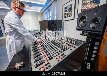 London, Großbritannien. Dezember 2023. Die EMI TG12345 Mk I Recording Console, die von den Beatles in den Abbey Road Studios verwendet wurde, um ihr bahnbrechendes Album „Abbey Road“ auf Anfrage (in der Reihenfolge von sieben Ziffern) aufzunehmen, mit Iain Macmillan, zwei Abzüge der Beatles on Abbey Road, 1969, Schätzung: £18.000 - 20.000 und Techniker in original Studio weißen Mänteln - Eine Vorschau auf The Sound of the Beatles: the „Abbey Road“ Konsolenverkauf in Bonhams Knightsbridge, London. Der Verkauf selbst findet am 14. Dezember in Knightsbridge statt. Guy Bell/Alamy Live News Stockfoto