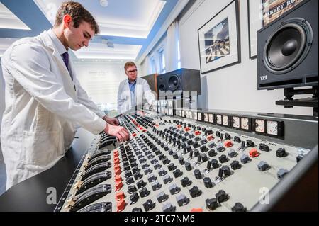 London, Großbritannien. Dezember 2023. Die EMI TG12345 Mk I Recording Console, die von den Beatles in den Abbey Road Studios verwendet wurde, um ihr bahnbrechendes Album „Abbey Road“ auf Anfrage (in der Reihenfolge von sieben Ziffern) aufzunehmen, mit Iain Macmillan, zwei Abzüge der Beatles on Abbey Road, 1969, Schätzung: £18.000 - 20.000 und Techniker in original Studio weißen Mänteln - Eine Vorschau auf The Sound of the Beatles: the „Abbey Road“ Konsolenverkauf in Bonhams Knightsbridge, London. Der Verkauf selbst findet am 14. Dezember in Knightsbridge statt. Guy Bell/Alamy Live News Stockfoto