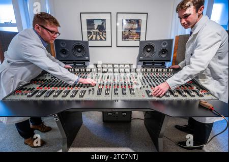 London, Großbritannien. Dezember 2023. Die EMI TG12345 Mk I Recording Console, die von den Beatles in den Abbey Road Studios verwendet wurde, um ihr bahnbrechendes Album „Abbey Road“ auf Anfrage (in der Reihenfolge von sieben Ziffern) aufzunehmen, mit Iain Macmillan, zwei Abzüge der Beatles on Abbey Road, 1969, Schätzung: £18.000 - 20.000 und Techniker in original Studio weißen Mänteln - Eine Vorschau auf The Sound of the Beatles: the „Abbey Road“ Konsolenverkauf in Bonhams Knightsbridge, London. Der Verkauf selbst findet am 14. Dezember in Knightsbridge statt. Guy Bell/Alamy Live News Stockfoto