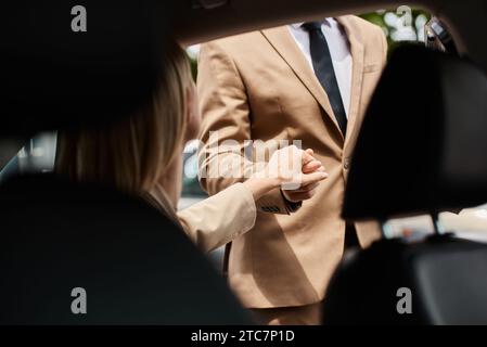 Zugeschnittene Ansicht eines stilvollen Mannes, der die Hand einer eleganten Frau in formeller Kleidung hält und auf der Straße aus dem Auto steigt Stockfoto