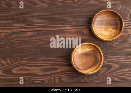 Zwei leere braune Holzschüssel auf braunem hölzernem Hintergrund. Draufsicht, Kopierraum, flache Ladefläche. Stockfoto
