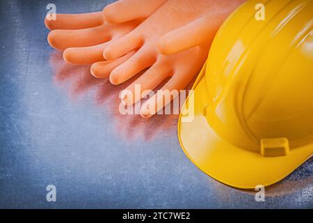 Isolierende Gummihandschuhe Bauhelm auf metallischem Hintergrund Elektrizitätskonzept Stockfoto