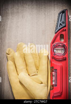 Arbeitshandschuhe aus Leder in roter Bauhöhe auf vertikaler Holzplatte Stockfoto