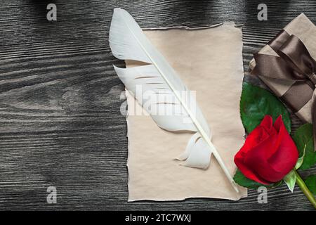 Vintage-Papier Feder rote Rose Geschenkbox auf Holzbrett Feiertagskonzept Stockfoto