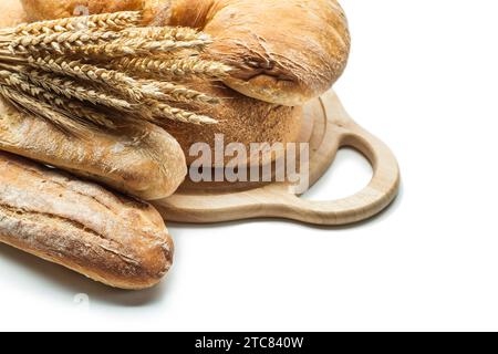 Brotlaibe und Weizenohren auf Schnitzerbrett isoliert Stockfoto