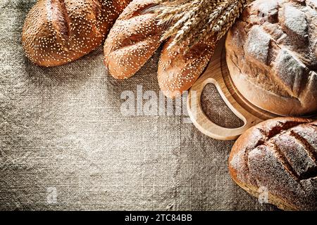 Schnitzerbrett braunes Brot Baguette Weizenohren auf Sacking Hintergrund Stockfoto