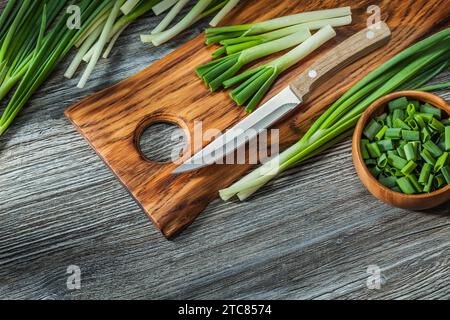 Gehackte grüne Frühlingszwiebeln Küchenmesser Holz Schneidebrett Vintage Holz Hintergrund Stockfoto