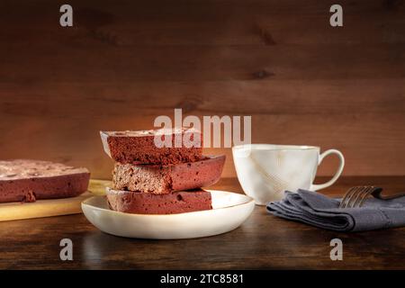 Schokoladen-Brownie mit Tee, einfacher Kaffeekuchen, ein seitlicher Blick auf einem dunklen rustikalen Holzhintergrund mit Kopierraum Stockfoto