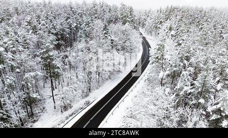 Atemberaubender Winterwald mit Reim und Schnee, geteilt durch Asphaltstraße, Polen. Verschneite Winter in der Natur. Stockfoto
