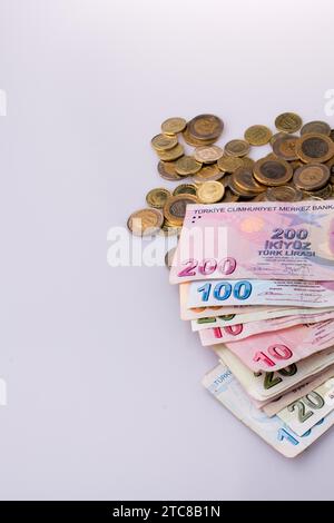 Türkische Lira-Münzen und-Banknoten nebeneinander auf weißem Hintergrund Stockfoto