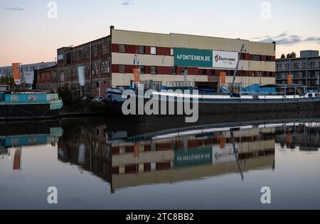 Vilvoorde, Flämische Brabant Region, Belgien, 28. November 2023 - altes Industriebau namens Kruitfabriek, das sich in der Abenddämmerung im Kanal spiegelt Stockfoto