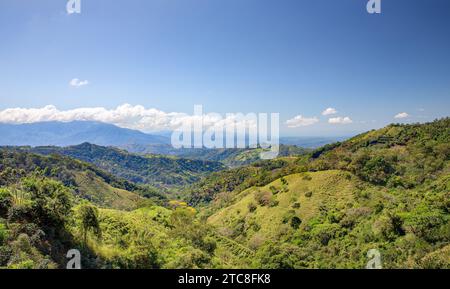 Wunderschönes grünes Bergtal mit blauem Himmel, niedrigen hängenden Wolken und Kopierraum. Berglandschaft in Costa Rica. Zu den Konzepten gehören Reisen, Stockfoto