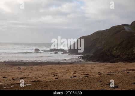 Poldhu, Cornwall, 11. Dezember 2023, Ein paar Leute gingen heute Nachmittag am Strand in Poldhu Cove entlang, trotz des langweiligen und trostlosen Wetters. Am Strand gab es immer noch Meeresschaum von all den neueren rauen Meeren. Quelle: Keith Larby/Alamy Live News Stockfoto