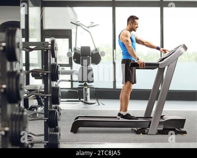 Profilaufnahme eines Mannes, der im Fitnessstudio auf dem Laufband dreht Stockfoto