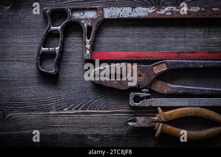 Rostige Vintage-Handsäge-Zange auf Holzbrett-Baukonzept Stockfoto