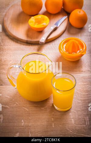 Saft in Glaskrug Messer Fruchtpresse auf Holztisch Stockfoto