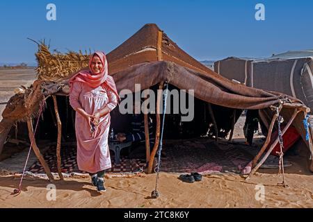 Nomadische Beduinenfrau mit Hijab und Mann servieren Tee im Zelt in der Sahara bei Merzouga, Drâa-Tafilalet, Errachidia, Marokko Stockfoto