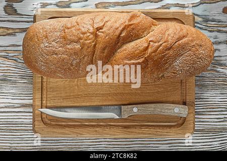 Schnitzerbrett langes Brotmesser auf Vintage-Holzoberfläche Stockfoto