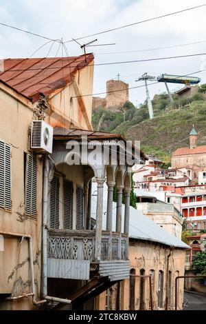 Reisen Sie nach Georgien - schäbiges Haus mit geschnitztem Holzbalkon in der Altstadt von Tiflis an bewölktem Herbsttag Stockfoto