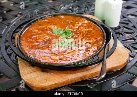 Reisen Sie nach Georgien - georgisches Gericht Ostri (gedünstete Fleischstücke in Sauce mit georgischen Gewürzen) in der Pfanne in einem lokalen Café im Freien in Tiflis Stadt Stockfoto