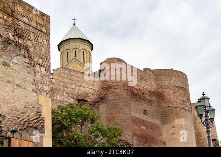 Reisen Sie nach Georgien - Blick von unten auf die Außenmauern der antiken Festung Narikala mit der Kirche des Heiligen Nikolaus auf dem Sololaki-Hügel in Tiflis im bewölkten Autu Stockfoto