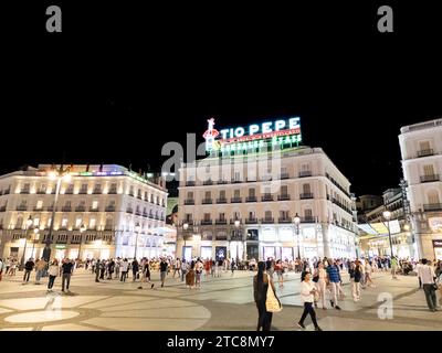 Madrid, Spanien - 29. August 2023: Das ikonische Tio Pepe Neonschild auf einem Gebäude, das die geschäftige Puerta del Sol bei Nacht darstellt Stockfoto