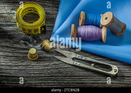 Nähwerkzeuge Spulen mit Gewinde Schere Fingerhülsen Maßband auf Vintage Holz Hintergrund Stockfoto