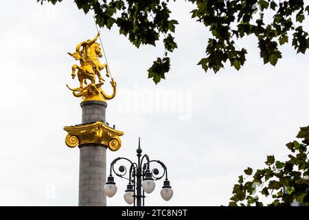 Tiflis, Georgien - 22. September 2023: Grüne Blätter und goldene Statue St. Georg tötet Drachen auf dem Liberty Monument auf dem Freedom Square in der Mitte Stockfoto