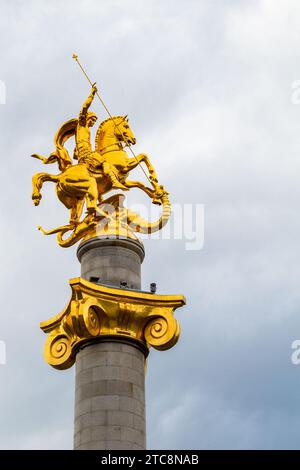 Tiflis, Georgien - 22. September 2023: Denkmal der Freiheit mit goldener Statue des Heiligen Georg, der Drachen auf dem Freiheitsplatz in Tiflis bei bewölktem Himmel tötet Stockfoto