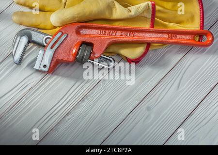 Roter Klempner-Affenschlüssel und gelbe Arbeitshandschuhe auf weißem Vintage-Holz Stockfoto