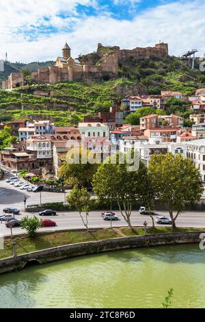 Tiflis, Georgien - 26. September 2023: Blick auf die Uferpromenade des Kura-Flusses und die ansierende Festung Narikala vom Aussichtspunkt Metekhi in Tiflis auf bewölktem Au Stockfoto