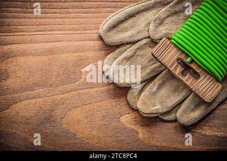 Sicherheitshandschuhe aus Leder mit Gartenbindedraht auf Holzbrett-Gartenkonzept Stockfoto