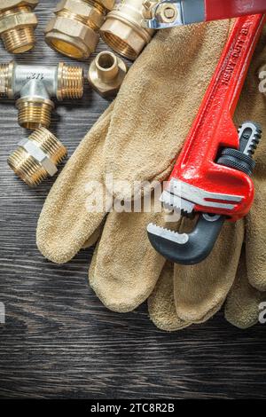 Rohrverbinder für Rohrverbinder mit Monkey-Schraubenschlüssel Schutzhandschuhe Wasserventil auf Holzbrett Stockfoto