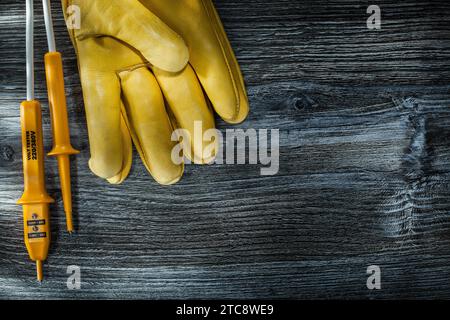 Schutzhandschuhe für Elektrotester auf Holzbrett Stockfoto