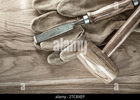 Blockhammer Flachmeißel Schutzhandschuhe auf Holzbrett Stockfoto