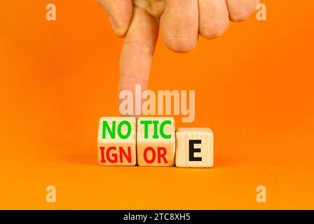 Symbol beachten oder ignorieren. Konzeptwort Hinweis oder Ignorieren auf Holzwürfeln. Schöner oranger Tisch mit orangefarbenem Hintergrund. Geschäftsmann Hand. Business Lifestyle Stockfoto