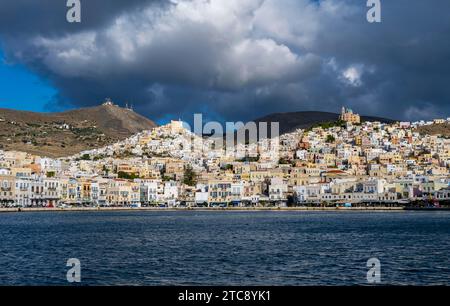 Blick auf die Stadt Ermoupoli mit pastellfarbenen Häusern und Meer, auf dem Hügel Anastasi Kirche oder Auferstehungskirche und Basilika San Stockfoto