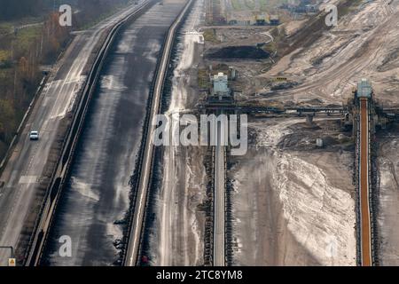 Braunkohle im Rheinischen Revier. Blick vom Aussichtpunkt kleiner Lindemann aus gesehen auf einen Teil des Braunkohle-Tagebaus Inden, wo Braunkohle durch die RWE Power AG abgebaut wird. Der Abbaubereich erstreckt sich über eine Fläche von rund viereinhalbtausend Hektar. Die dort geförderte Braunkohle dient ausschließlich der Fütterung des Braunkohlekraftwerkes Weisweiler in unmittelbarer Nähe. Im Bild Transportbänder bzw. Förderbänder neben einer Straße. Düren Nordrhein-Westfalen *** Braunkohle im Rheinischen Bergbaugebiet Ansicht eines Teils des Braunkohlebergwerks Inden, wo Braunkohle liegt Stockfoto